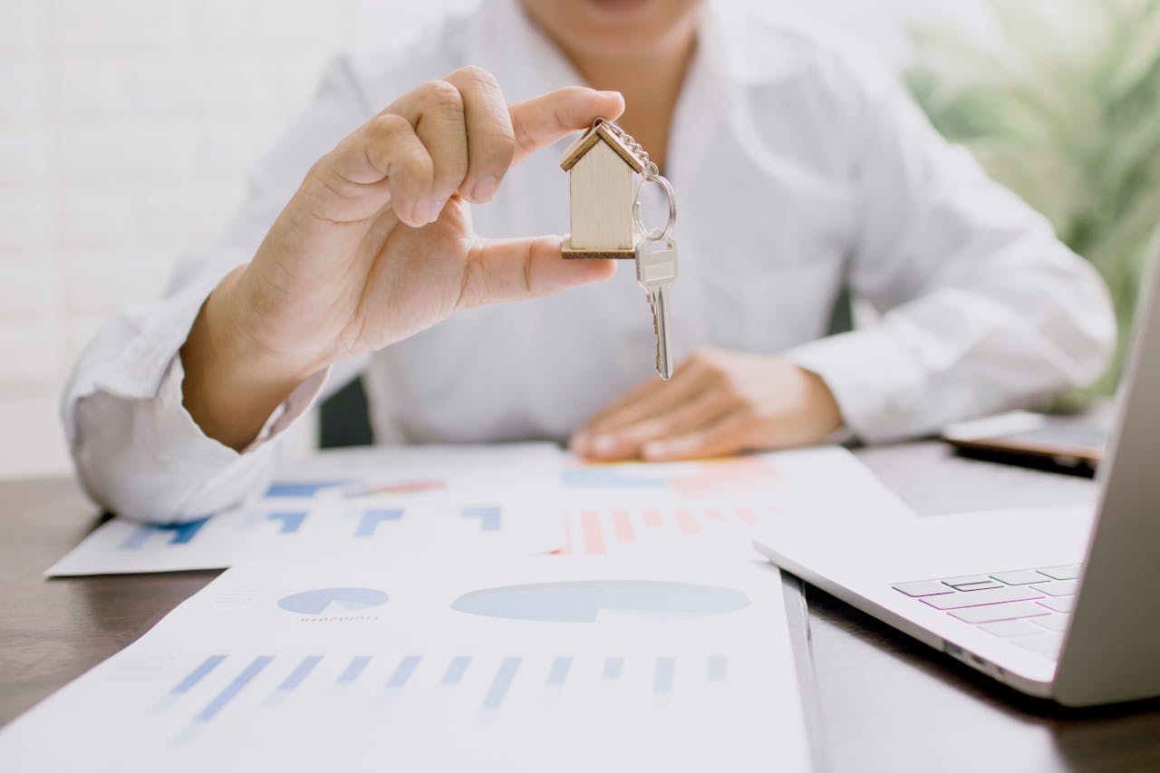 Home Real estate professional presenting a house model with keys, symbolizing property investment and ownership.